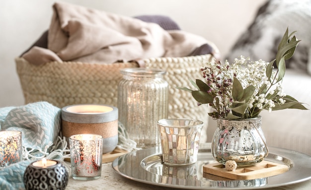 Décorations pour la maison à l'intérieur. Une couverture turquoise et un panier en osier avec un vase de fleurs et de bougies