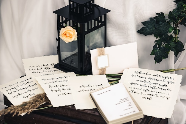 Décorations pour le mariage: lanterne en métal noir, rose, brindille de lierre, canne, papier vintage avec beau texte, enveloppe, boîte, carte postale.