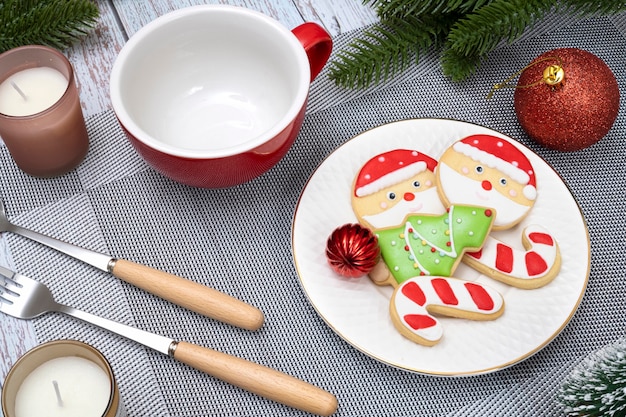 Décorations de table de Noël avec une tasse en céramique rouge et une assiette de biscuits au sucre