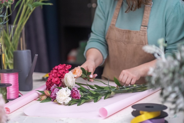 Décoratrice de fleurs experte utilisant ses mains pour créer un magnifique bouquet de roses roses slower shop