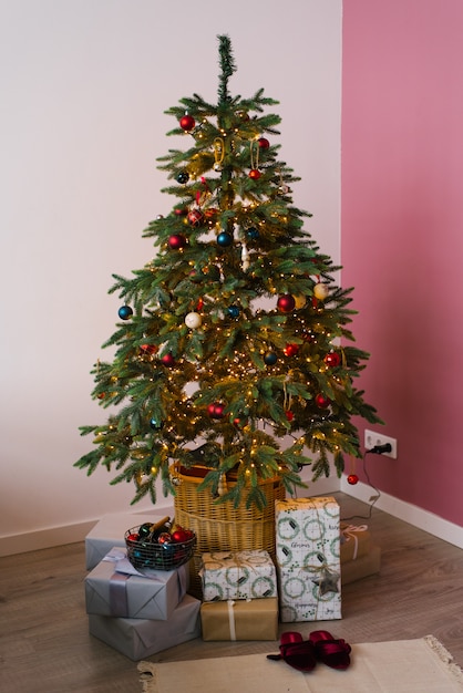 Décoré pour arbre de Noël et du nouvel an avec des cadeaux en dessous dans le salon en rose