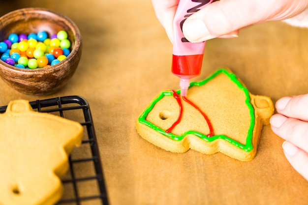 Décorer des biscuits au pain d'épice avec du glaçage royal et des bonbons colorés.