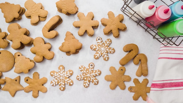 Décorer des biscuits au pain d'épice avec du glaçage royal pour Noël.