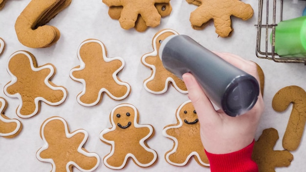 Décorer des biscuits au pain d'épice avec du glaçage royal pour Noël.