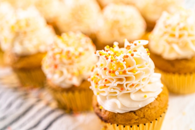 Décorer un cupcake aux épices à la citrouille avec de la crème au beurre italienne et des vermicelles.