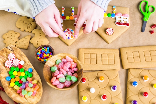 Décorer la maison en pain d'épice avec du glaçage royal et des bonbons colorés.