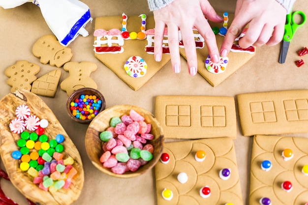 Décorer la maison en pain d'épice avec du glaçage royal et des bonbons colorés.