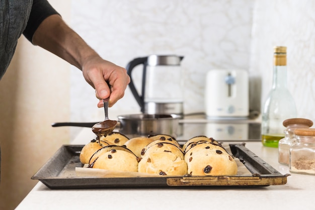 Décorer des petits pains croisés chauds avec du chocolat chaud