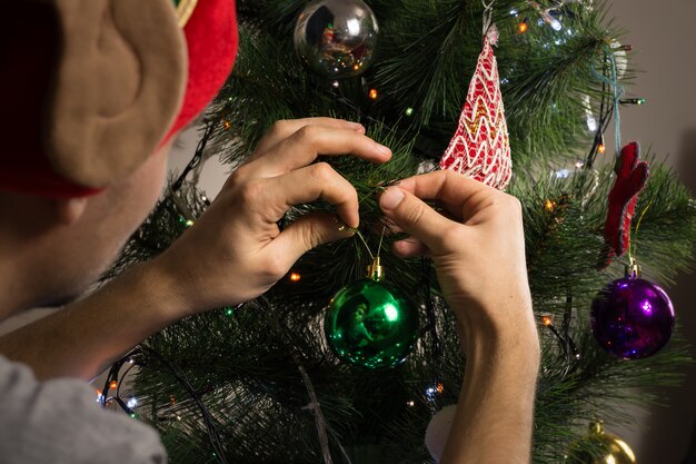 Décorer un sapin avec des lanternes, des guirlandes et des jouets brillants