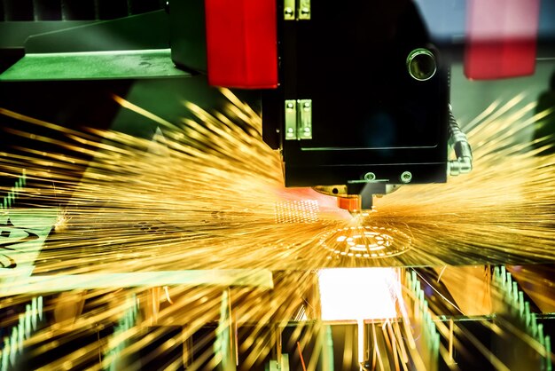 Découpe laser CNC du métal, technologie industrielle moderne. Petite profondeur de champ. Attention - prise de vue authentique dans des conditions difficiles. Un peu de grain et peut-être flou.