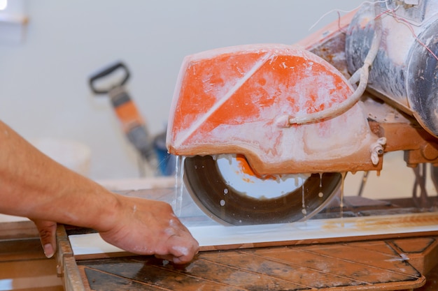 Découpe manuelle de carreaux de céramique sur une machine spéciale pour la découpe de carreaux.