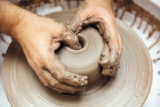 Découvre à un artiste fait la poterie d'argile sur une roue de rotation