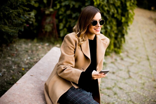 Photo découvre à la femme moderne à l'aide de téléphone portable à l'automne en plein air