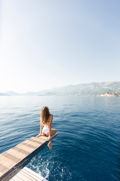 Découvre à jeune femme séduisante, assis sur un yacht de luxe flottant en mer