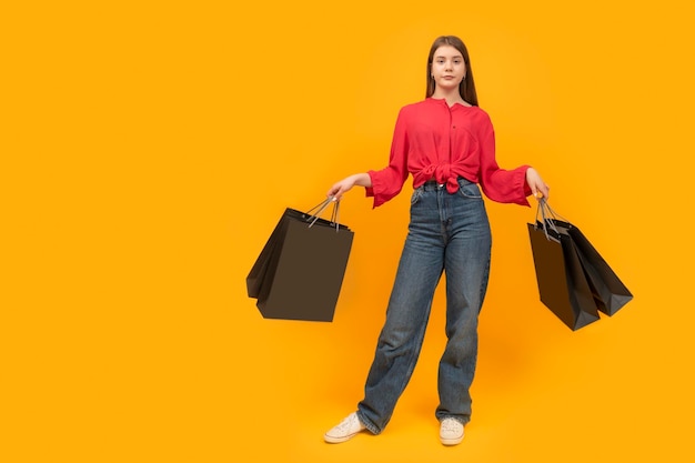 Déçu jeune fille avec des sacs en papier dans ses mains Après le concept de magasinage Fond jaune vif Copiez l'espace