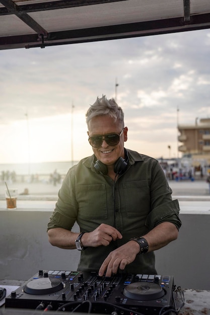 Deejay mixant en plein air avec la lumière du soleil arrière Portrait d'un disc-jockey jouant de la disco ou de la musique profonde pour les personnes lors d'une fête sur la plage au coucher du soleil Concept de divertissement et de divertissement d'été et de fête