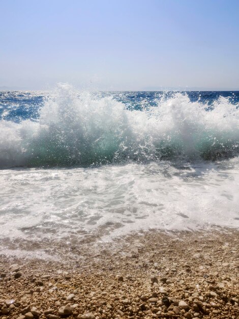 Déferlante de l'océan bleu sur la plage de galets fond d'été