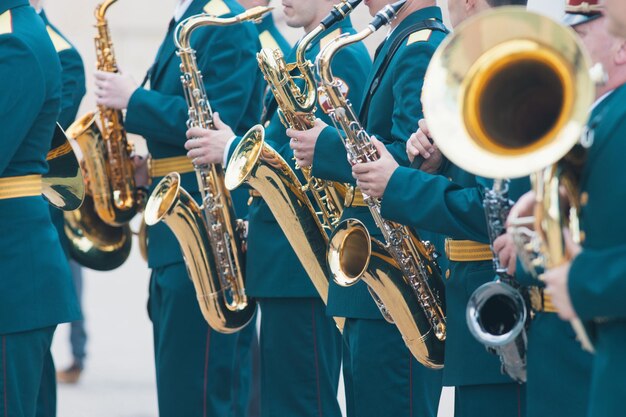Un défilé d'instruments à vent en costumes verts tenant un saxophone