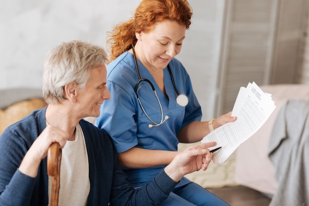 Photo définir la cause de la maladie. incroyable médecin persistant positif parlant à son patient et lui expliquant quelques détails de son traitement