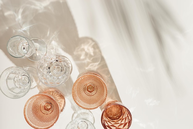 Définir des verres colorés en verre transparent et beige avec de belles ombres de feuille de palmier à la lumière du soleil boisson d'été pour les événements vin blanc eau dans des verres tendance vue de dessus esthétique