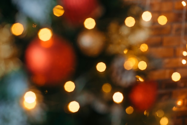 Défocalisation décorée agrandi de sapin de Noël. Boules rouges et dorées et guirlande lumineuse avec lampes de poche