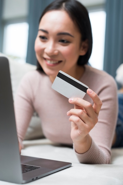 Photo défocalisé femme tenant une carte de crédit essayant d'acheter en ligne