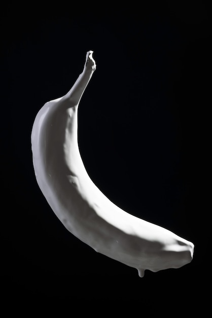 Dégoulinant de peinture blanche de banane sur fond noir