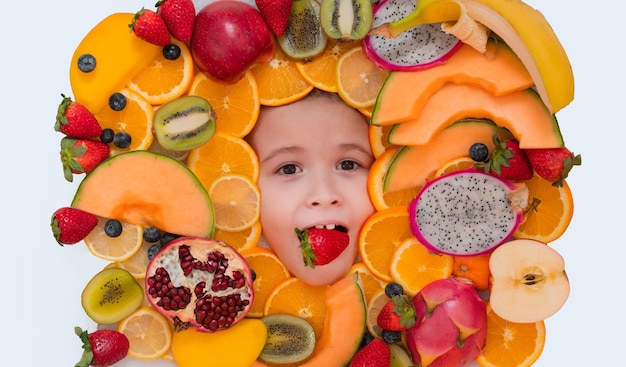 Dégustation de fruits fraise pour enfants dans la bouche de l'enfant vitamines saines fruits enfants face avec mélange de fru frais