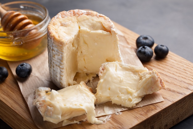 Dégustation d&#39;un plateau de fromages sur une assiette en pierre sombre.