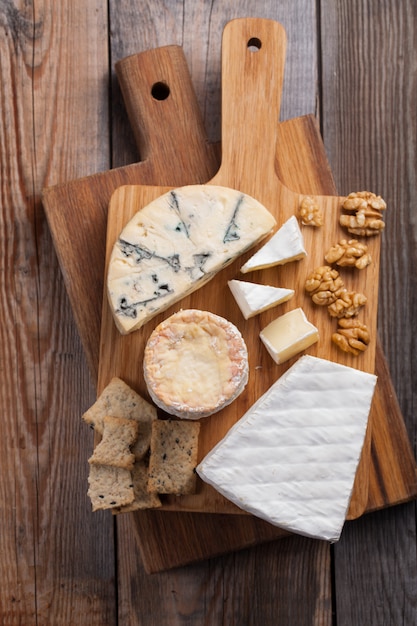 Dégustation d&#39;un plateau de fromages sur un fond en bois.