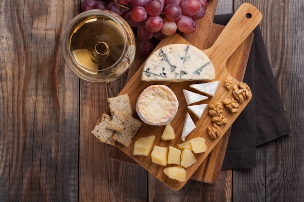 Dégustation d&#39;un plateau de fromages sur un fond en bois.