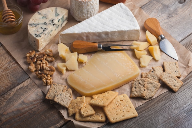 Dégustation d&#39;un plateau de fromages sur un fond en bois.