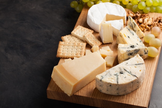 Dégustation d&#39;un plateau de fromages sur une plaque de bois.