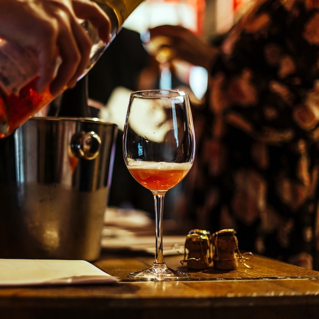 Dégustation de vin: sur une table en bois se trouve un verre de champagne rose.