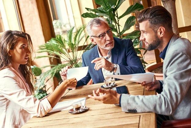 Déjeuner d'affaires trois personnes au restaurant assis à table pour discuter de l'équipe concentrée du projet