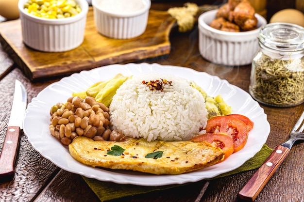 Déjeuner brésilien typique riz et haricots filet de poulet grillé et frites cuisine maison cadre rustique