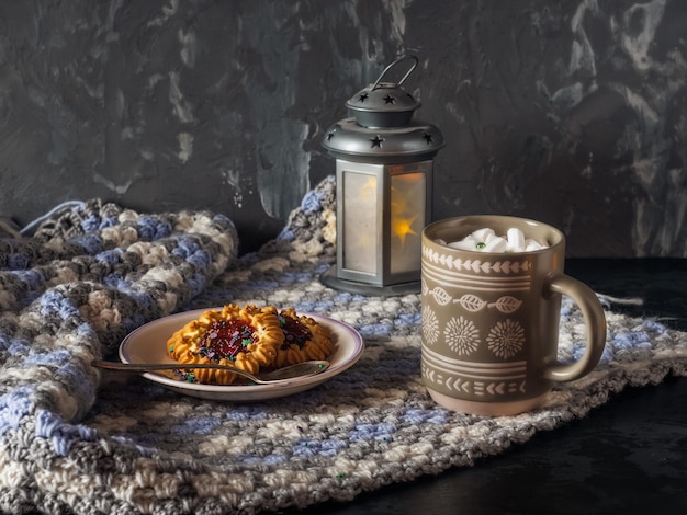 Photo déjeuner avec café et biscuits. café avec marshlelow dans une tasse grise, biscuits sablés sur une assiette en céramique, servi sur un plaid tricoté