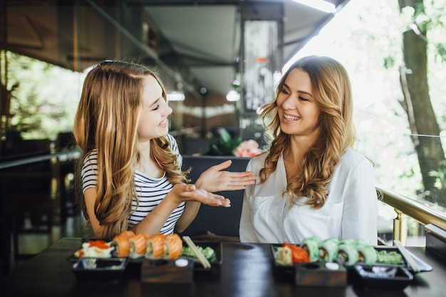 Déjeuner Dans Un Restaurant Chinois Sur La Terrasse D'été. Maman Et Sa Belle Jeune Fille Mangent Des Sushis Avec Des Bâtons Chinois