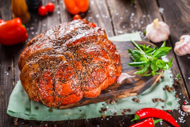 Délicatesse de viande, beau porc bouilli, entier ou tranché sur une planche à découper de cuisine sombre et morose