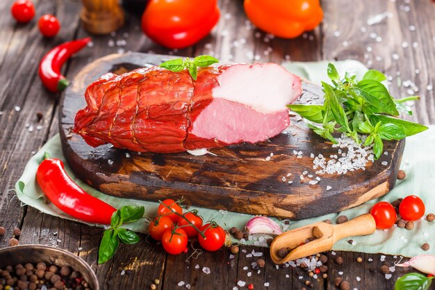 Délicatesse de viande, beau porc bouilli, entier ou tranché sur une planche à découper de cuisine sombre et morose