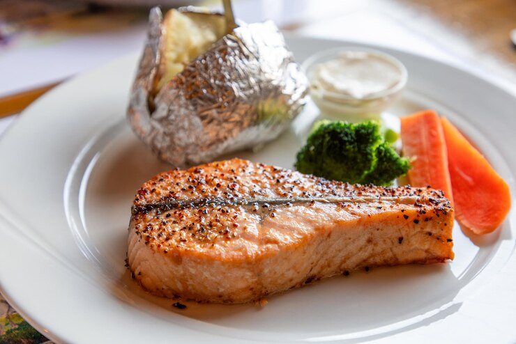 Photo une délicieuse assiette de saumon norvégien parfaitement grillé avec des pommes de terre au four, des carottes de brocoli fraîches et une sauce riche.