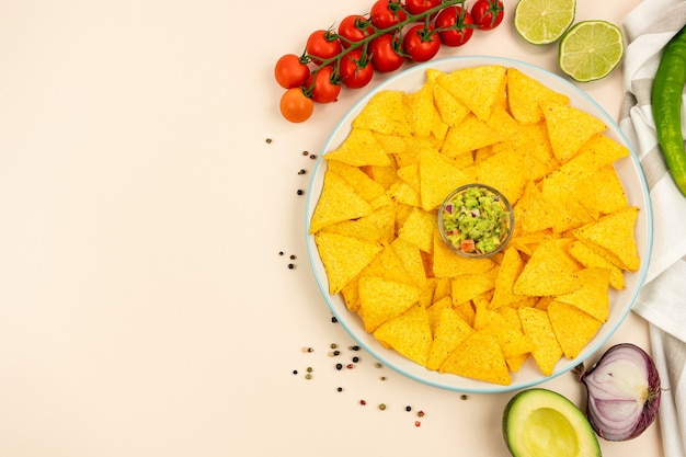 Une délicieuse assiette de tortillas nachos sauce guacamole oignons rouges tomates limes olives