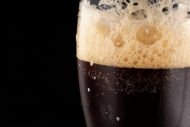 Délicieuse bière brune avec place en gros plan de mousse