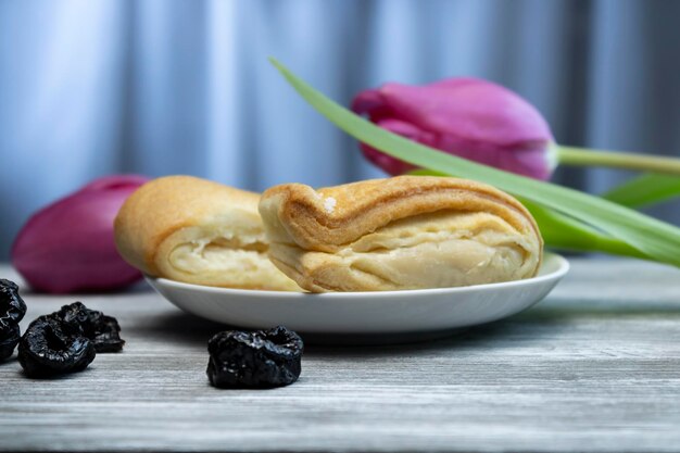 Photo délicieuse bouffée avec des tulipes lilas en arrière-plan et une dispersion de fruits secs en arrière-plan