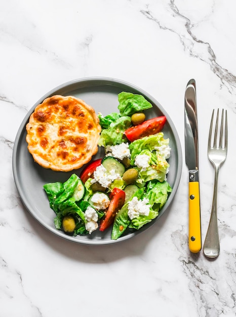Délicieuse collation mini quiche de mozzarella au thon en conserve et salade grecque sur fond clair vue de dessus