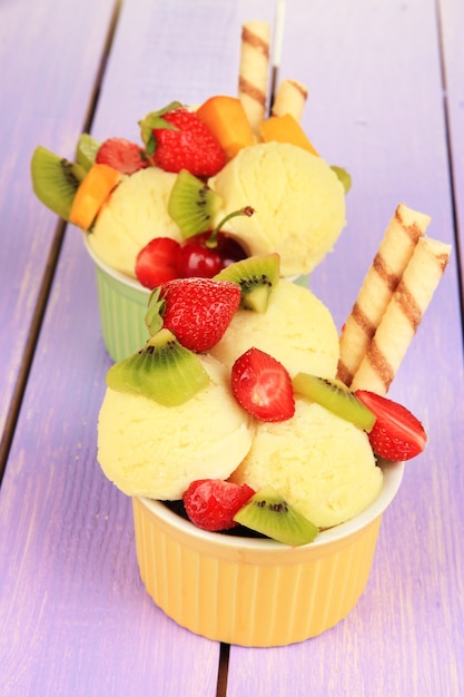 Délicieuse crème glacée aux fruits et baies dans un bol sur la table en bois