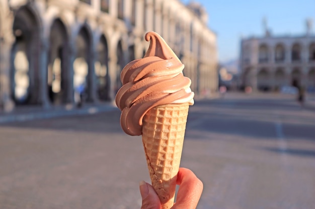 Délicieuse crème glacée molle au chocolat et à la vanille à la main contre des bâtiments vintage flous