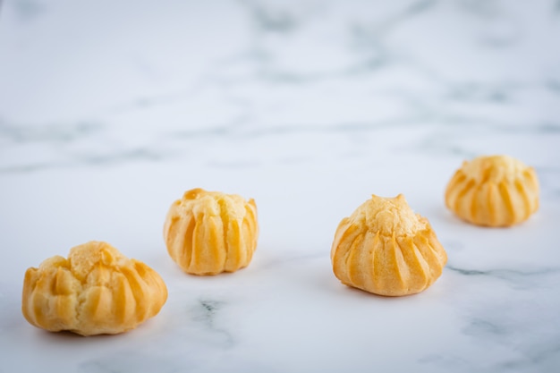 Délicieuse crème à la vanille eclair, pâte à choux remplie d'une crème, boulangerie maison sur fond de marbre blanc pour concept de collation