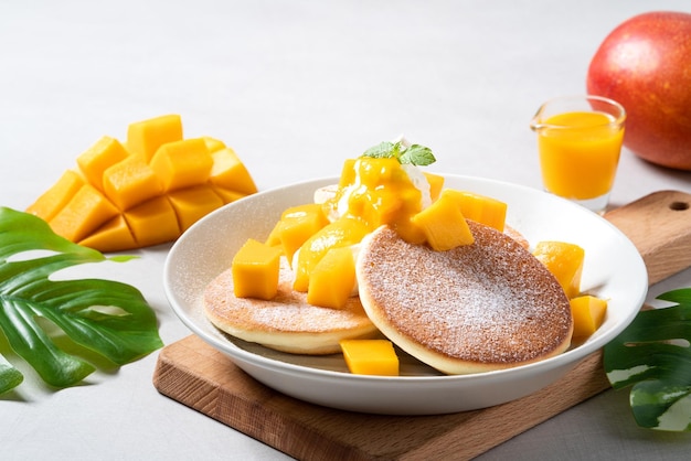 Délicieuse crêpe soufflée japonaise avec des dés de mangue et de la confiture sur fond de table gris