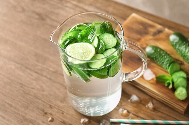 Délicieuse eau rafraîchissante à la menthe et au concombre en pot sur une table en bois